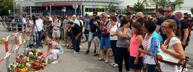 Passanten gedenken am 23.07.2016 nahe dem Olympia-Einkaufszentrum (OEZ) in München, einen Tag nach einer Schießerei mit Toten und Verletzten, den Opfern.
