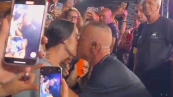 Mann küsst Frau bei einem Konzert.