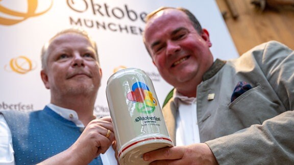 Der Grafiker Manfred Escher (l) und Peter Inselkammer (r), Sprecher der Wiesn-Wirte stellen den offiziellen Wiesn-Maßkrugs 2023 vor. 