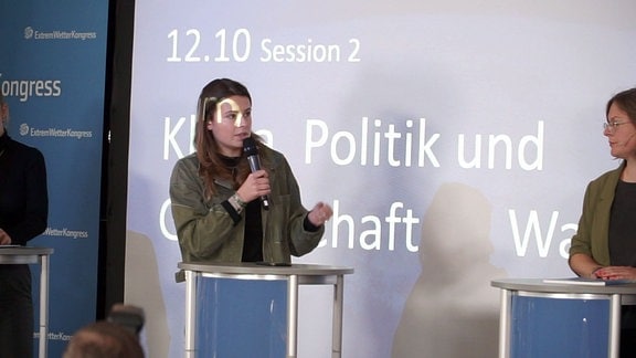 Frau spricht am Mikrofon während einer Konferenz.