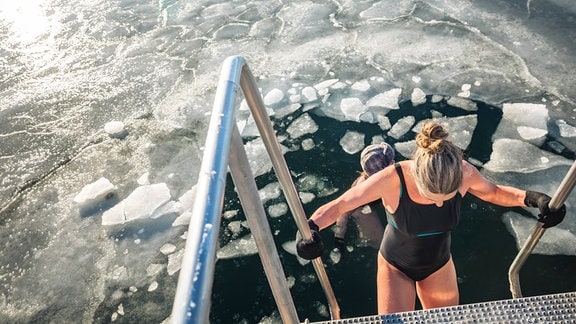 Zwei Winterbader schwimmen mit Eisbrocken an einem sonnigen Tag