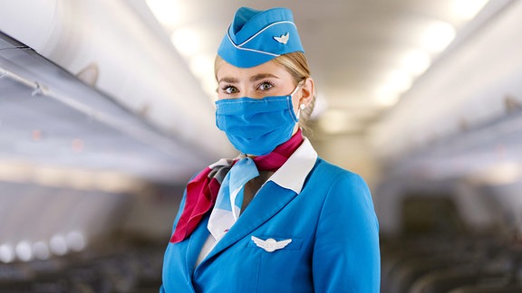 Stewardess von Eurowings mit Maske im Mittelgang eines Flugzeuges.