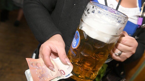Die Bedienung Dayana hält eine Maß Bier und 15 Euro im Hofbräuzelt in Ihren Händen. 