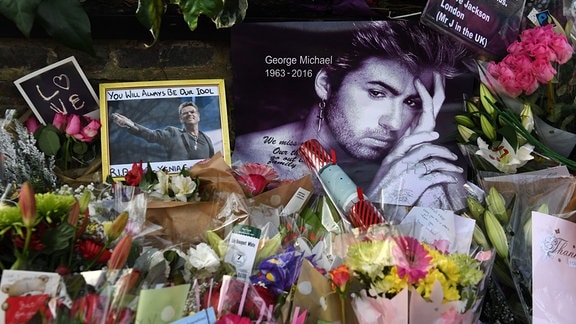 Eine Gedenkstelle mit Blumen und Bildern von George Michael