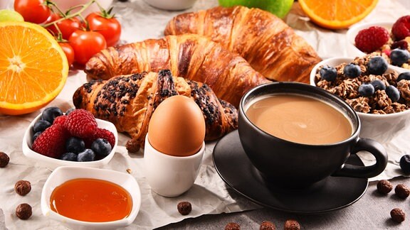 Frühstück mit Kaffee, Croissants, Obst und Ei.