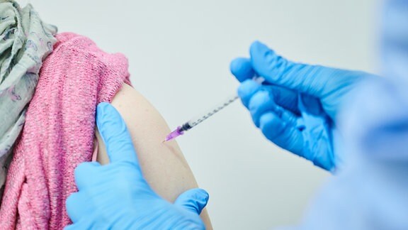 Eine Person bekommt im Impfzentrum im Ring-Center Berlin ihre Auffrischungsimpfung mit dem neuen angepassten Impfstoff.