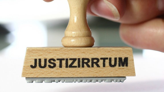 Stempel in der Hand mit der Aufschrift "Justizirrtum".