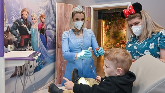 Anne Heinz (l), Kinderzahnärztin, verkleidet als Eiskönigin «Elsa» und ihre Arzthelferin Ari Dema mit ihrem zweijährigen Sohn Diar in der Kinderzahnarztpraxis «Dentiland».
