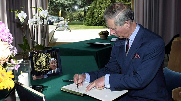 Der britische Prinz Charles unterzeichnet ein Kondolenzbuch.
