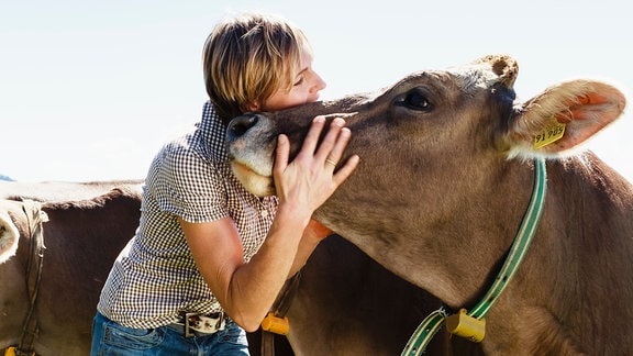 Eine Frau kuschelt mit einer Kuh.