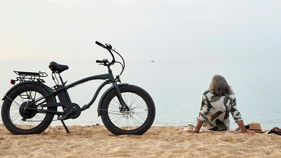ein Mann mit Fahrrad sitzt am Strand