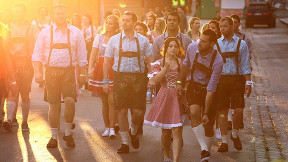 Besucher laufen am Eröffnungstag des Oktoberfestes in München (Bayern) in der Morgensonne