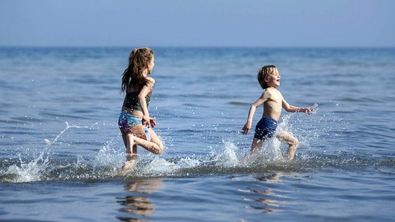 Kinder laufen durch`s flache Ostseewasser.