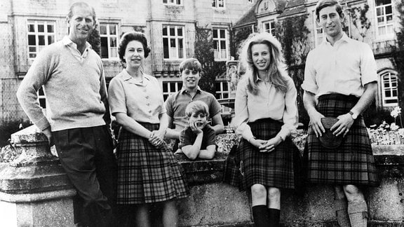 Historisches Schwarzweissfoto: Die englische Königin Queen Elizabeth II mit ihrer Familie vor einem Schloss