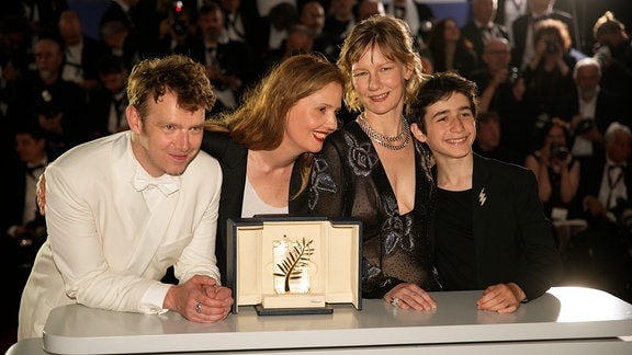 Justine Triet (2.v.l), Gewinnerin der Goldenen Palme für «Anatomy of a Fall», Antoine Reinartz (l), Sandra Hüller und Milo Machado Graner (r) posieren für Fotografen während eines Fototermins nach der Preisverleihung bei den 76. internationalen Filmfestspielen in Cannes.