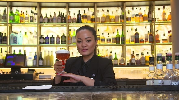 Barkeeperin hält einen Drink
