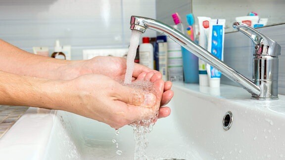 Eine Person wäscht Hände in fliessendem Wasser.