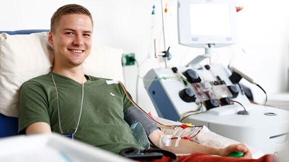 Ein junger lächelnder Mann auf Krankenbett bei Stammzellenspende.