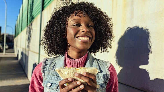 Fröhliches Mädchen mit einem Sandwich auf der Straße