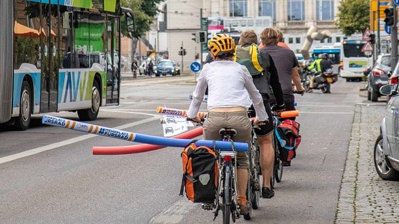 Fahrradfahrer mit Poolnudeln als Abstandshalter