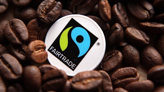 Ein Chip mit dem Logo "Fairtrade" inmitten von Kaffeebohnen. 