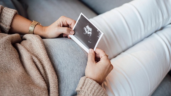Eine Schwangere Frau hält ein Ultraschallfoto.
