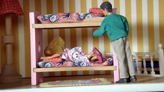 Puppen, ein Mann und ein Mädchen in einem Stockbett.