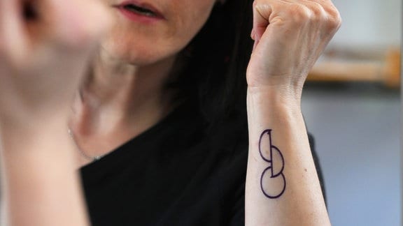 Eine Frau betrachtet das Design ihres neuen Organspende-Tattoos im Spiegel