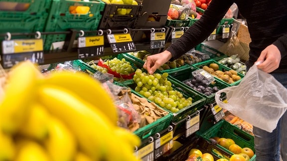 Ein Mann packt 2018 in einem Supermarkt Obst in einen Plastikbeutel.