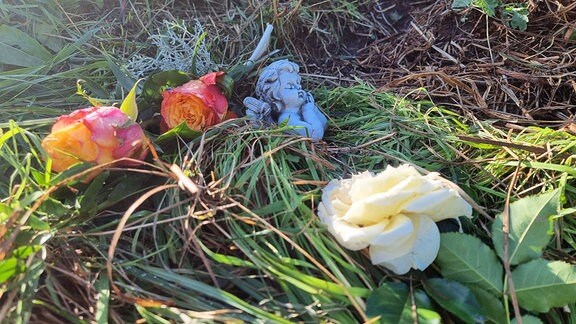 Blumen und eine Engelsfigur liegen am Tatort im niedersächsischen Landkreis Diepholz. Nach dem gewaltsamen Tod einer 17-Jährigen laufen die Ermittlungen auf Hochtouren. 