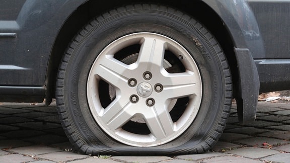 An einem Auto sind der Lack zerkratzt und die Reifen zerstochen.