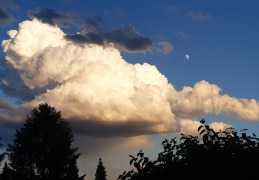 Sonne spiegelt sich in Wolke und der Mond zeigt sich