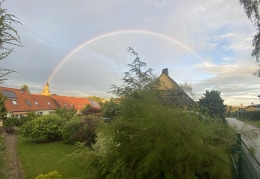 Voller Regenbogen taucht in Kirchenspitze von Oederan ein