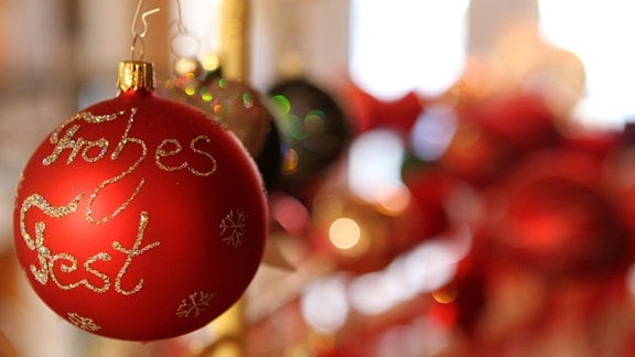 "Frohes Fest" steht auf einer roten Weihnachtskugel