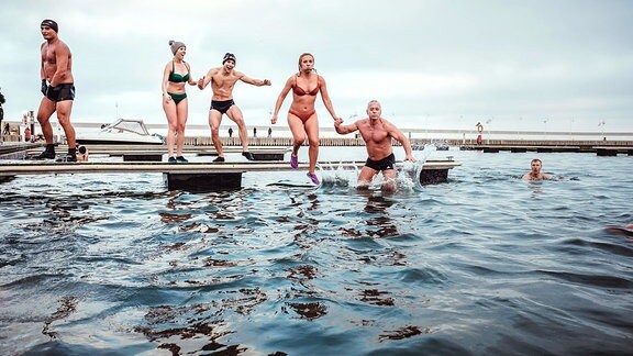 Eisbaden in der Danziger Bucht - eine mutige Frau springt von einem Steg ins Wasser.
