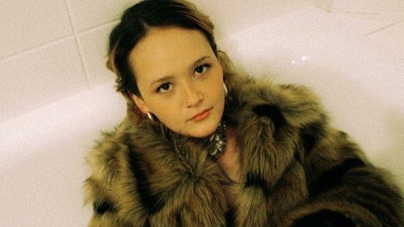 Liska, eine junge Frau in einem Pelzmantel liegt in einer Badewanne