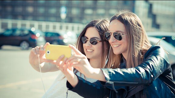 Zwei Frauen fotografieren sich mit einem Smartphone selber.