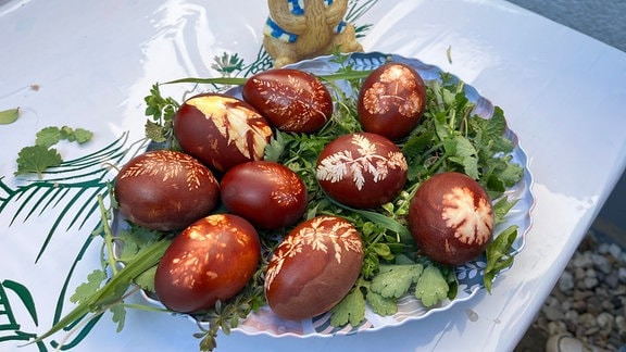 Mehrere mit Naturfarben gefärbte Ostereier liegen auf einem Teller.