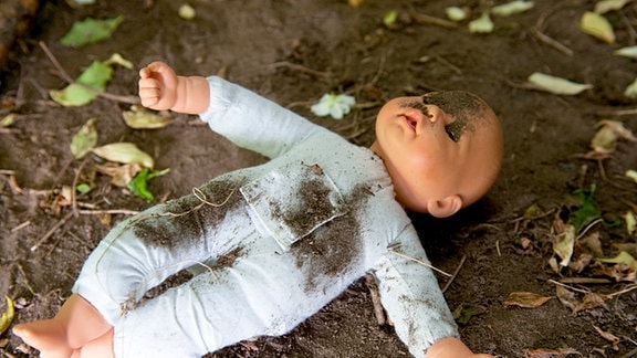 Themenbild: Kindesmisshandlung - Eine Puppe liegt im Schmutz auf dem Boden.