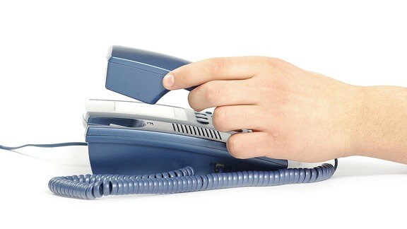 Eine Hand greift nach einem Telefonhörer