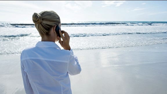 Eine Frau telefoniert im Urlaub mit ihrem Handy