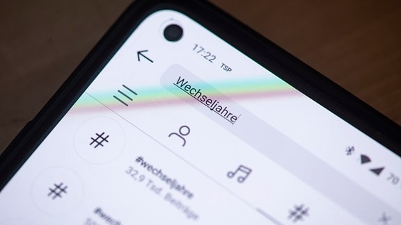 Auf dem Bildschirm eines Smartphones steht das Wort Wechseljahre im Suchfeld der App Instagram geschrieben