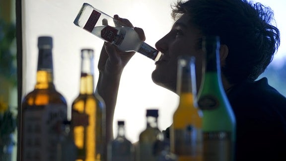 Ein Jugendlicher sitzt 2009 hinter Flaschen mit Alkohol und trinkt ein alkoholhaltiges Mixgetränk.