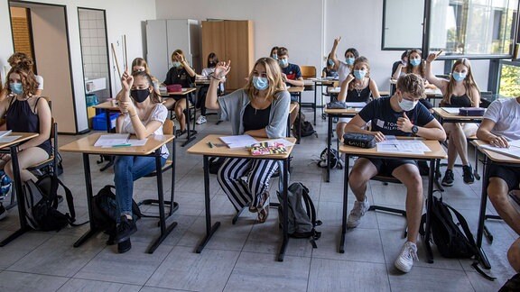 Schüler sitzen mit Mund- , Nasenschutz im Unterricht