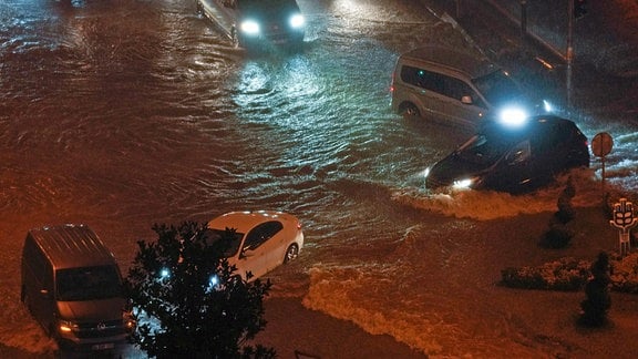 Autos fahren durch Hochwasser, das die Straße aufgrund von starkem Regen überschwemmt.