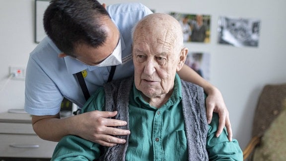 Altenpfleger redet mit einem Bewohner im Pflegeheim