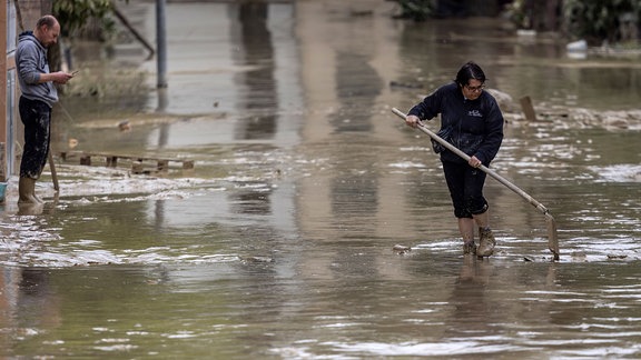 Anwohner versuchen nach Überschwemmungen eine Straße von Schlamm und Wasser zu befreien. 
