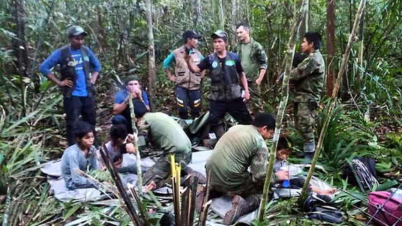 Auf diesem von der Pressestelle der kolumbianischen Streitkräfte veröffentlichten Foto kümmern sich Soldaten und indigene Männer um die vier Geschwister, die nach einem tödlichen Flugzeugabsturz vermisst wurden, im Dschungel von Solano im kolumbianischen Bundesstaat Caqueta.