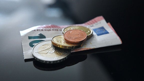 Münzen und ein Geldschein im Wert von 12,41 Euro liegen auf einer schwarzen Fläche (gestellte Szene).
