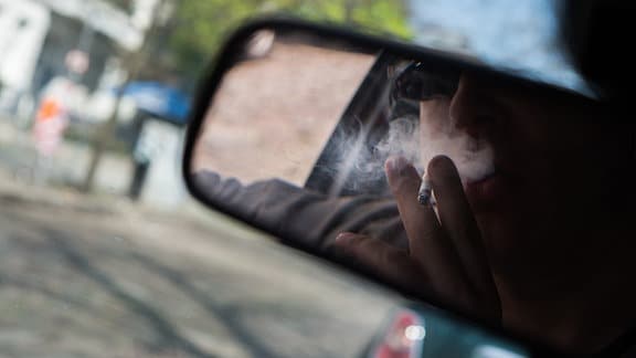 Ein Mann raucht am 15.04.2018 in Berlin in seinem Auto eine Zigarette (gestellte Szene).